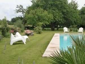 - un jardin avec une piscine, 2 chaises et une table dans l'établissement Du Côté de l'Ombrière, à Geay