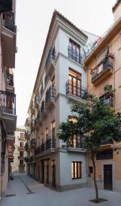 a white building with balconies and a tree in front of it at Old Town Flats Casa Burguerini in Valencia