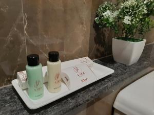 un bancone del bagno con due bottiglie di crema di Liza Regency a Chennai
