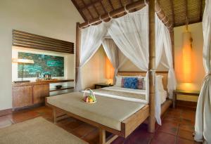 a bedroom with a canopy bed and a bathroom at Jeeva Klui Resort in Senggigi
