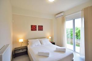 a bedroom with a white bed and a large window at Villa Nopigia Mare in Kissamos