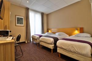 a hotel room with two beds and a desk at Hotel le Noailles Nice Gare in Nice