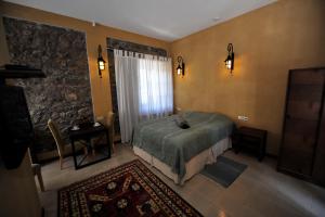 um quarto com uma cama, uma mesa e uma janela em Tufenkian Old Dilijan Complex em Dilijan