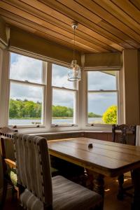 a dining room with a wooden table and three windows at The Boathouse in Rollesby