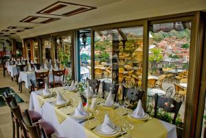 a dining room with tables and chairs and windows at Hotel Kopala in Tbilisi City