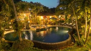 una piscina en un complejo con palmeras en Hotel Suma, en Lovina