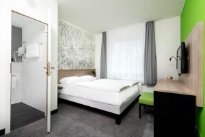 a bedroom with a white bed and a green wall at ibis Styles Halle in Halle an der Saale +57 photos