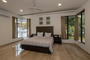 a bedroom with a bed in a room with windows at SaffronStays Vedanta, Lonavala - villa with lawn, plunge pool and indoor games near Tungarli Lake in Lonavala +17 photos