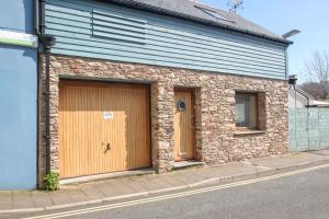 a brick building with two garage doors on a street at Farriers in Dartmouth