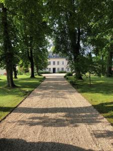 een grindweg die leidt naar een groot wit huis bij Chambres D'hôtes le clos de la Bertinière petit déjeuner inclus in Bosgouet
