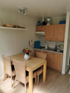 eine Küche mit einem Holztisch mit Stühlen und einer Vase aus Blumen in der Unterkunft Campinghütte in Fehmarn