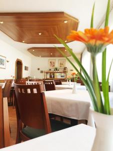 a restaurant with a table and a vase of orange flowers at Hotel Wegener in Mannheim