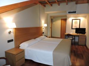 a bedroom with a white bed and a desk with a computer at Hotel El Nogal in Valladolid