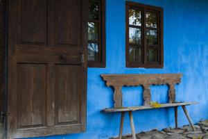 a door and a bench in front of a blue wall at Count Kálnoky's Transylvanian Guesthouses in Micloşoara
