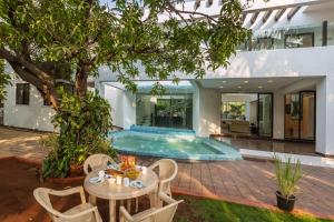 a patio with a table and chairs in front of a house at SaffronStays Vedanta, Lonavala - villa with lawn, plunge pool and indoor games near Tungarli Lake in Lonavala