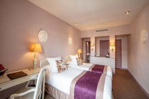 a hotel room with a bed and a desk and a bed at Le Cavendish in Cannes +37 photos