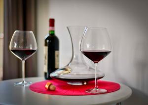 two wine glasses on a table with a bottle of wine at Welcome Traveller DIVINE CÉCILE in Garda