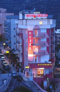 un edificio con una señal de neón en el costado. en Hotel Grillo en Nuoro
