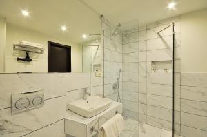 y baño blanco con lavabo y ducha. en Tekla Palace By Urban Hotels, en Tiflis