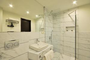 a white bathroom with a sink and a shower at Tekla Palace By Urban Hotels in Tbilisi City