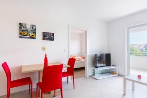 a living room with a dining room table and red chairs at Apartment SALE EL SOL in Medulin