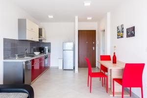 cocina y comedor con sillas rojas y mesa en Apartment SALE EL SOL, en Medulin