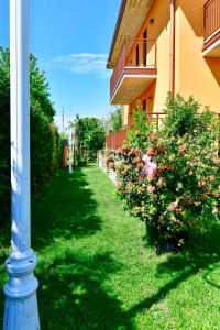 un poste en la hierba junto a un edificio con flores en Welcome Traveller DIVINE CÉCILE, en Garda