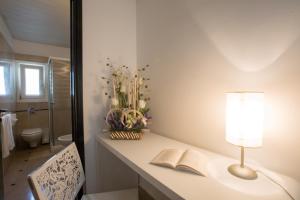 ein Badezimmer mit einem Tisch mit einer Lampe und einem Buch in der Unterkunft Hyencos Hotel Callyon in Torre San Giovanni Ugento