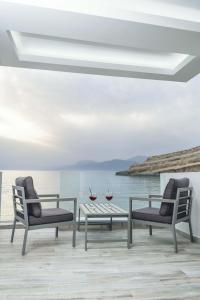 two chairs and a table on a deck with the ocean at Thalassoresort DOWNSTAIRS in Matala