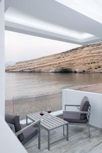 a patio with a table and chairs and the ocean at Thalasso resort in Matala