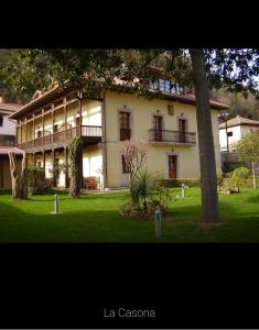 ein großes weißes Haus mit einem Baum im Hof in der Unterkunft La Casona de Don Santos in Proaza
