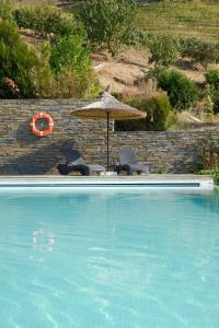 a swimming pool with two chairs and an umbrella at Hotel Rural Quinta Do Pego in Tabuaço