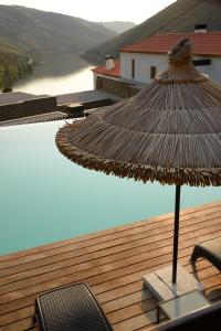 a straw umbrella sitting on a deck next to a pool at Hotel Rural Quinta Do Pego in Tabuaço