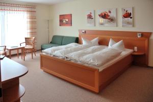 ein Schlafzimmer mit einem großen Bett und einer Couch in der Unterkunft Hotel Zur Wildtränke in Spremberg
