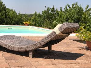una sedia in rattan seduta accanto alla piscina di Trullo delle Querce Suite Private Pool a Martina Franca