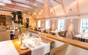 een restaurant met witte tafels, stoelen en ramen bij Hotel Kleines Meer in Waren