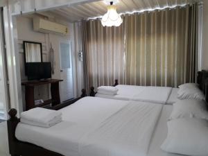 a bedroom with two white beds and a television at Farsai Homestay in Lop Buri