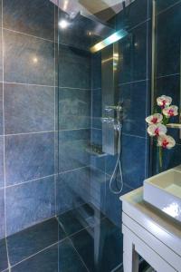 y baño con ducha de azulejos azules. en Cosmopolitan Hotel & Spa, en Paralia Katerinis