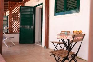 una mesa y una silla junto a un edificio con una puerta verde en Il corallo rosso, en Favignana