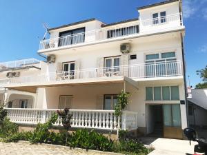 a white house with a balcony at Apartment & Rooms Riva in Vodice