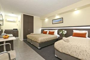 a hotel room with two beds and a desk at Morphettville Motor Inn in Glenelg