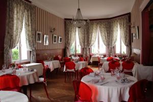 a dining room with white tables and red chairs at Hôtel de Paris Restaurant BISTRONOMY in Les Andelys