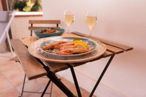 a table with a plate of shrimp and two glasses of wine at Il corallo rosso in Favignana