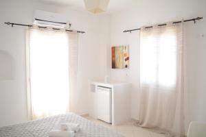 a white bedroom with a bed and a window at Maistrali in Provatas