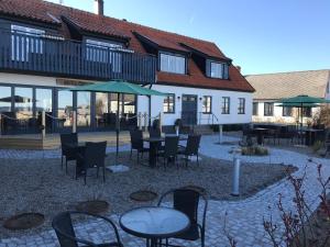 un patio avec des tables et des chaises en face d'un bâtiment dans l'établissement Bobergs på Hamngården, à Brantevik