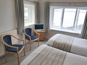 une chambre avec deux lits et un bureau avec une télévision dans l'établissement Ferry House Inn, à Milford Haven
