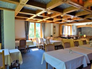a dining room with white tables and chairs and windows at Hotel Bündnerhof in Davos