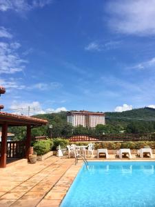 a swimming pool with chairs and a building in the background at Casa em Águas de Lindóia! in Águas de Lindóia