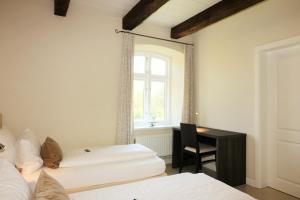 a bedroom with two beds and a desk and a window at Apartments Lille Hus in Sankt Peter-Ording