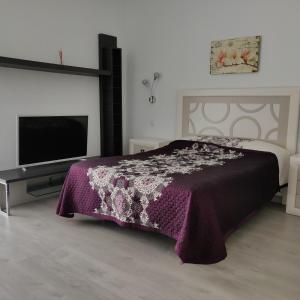 1 dormitorio con 1 cama de color púrpura y TV en Studio Anna - Playa Paraiso Tenerife, en Adeje